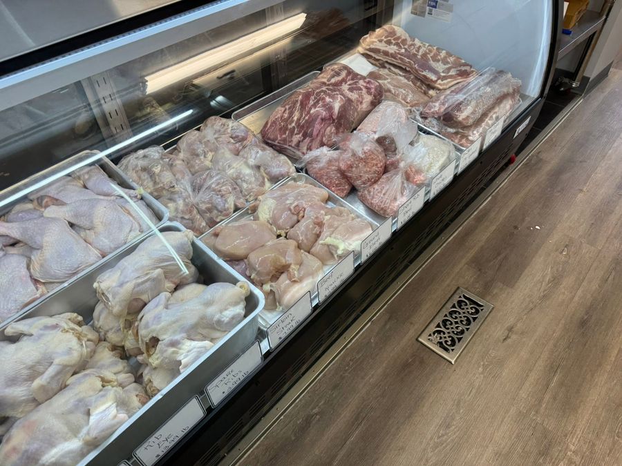 Butcher display case filled with fresh chicken, beef, and pork cuts