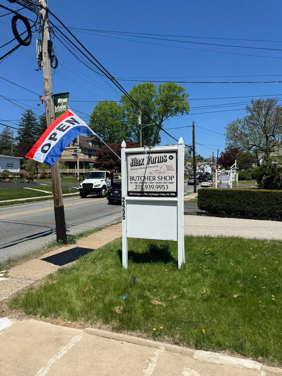 Max Farms Butcher Shop roadside sign with Open flag